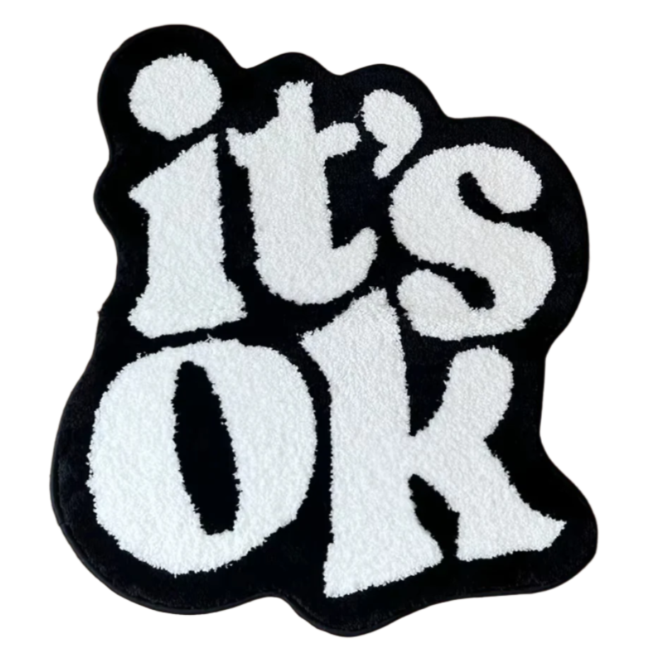 Minimalist tufted rug with "It’s Ok" text in soft neutral font.